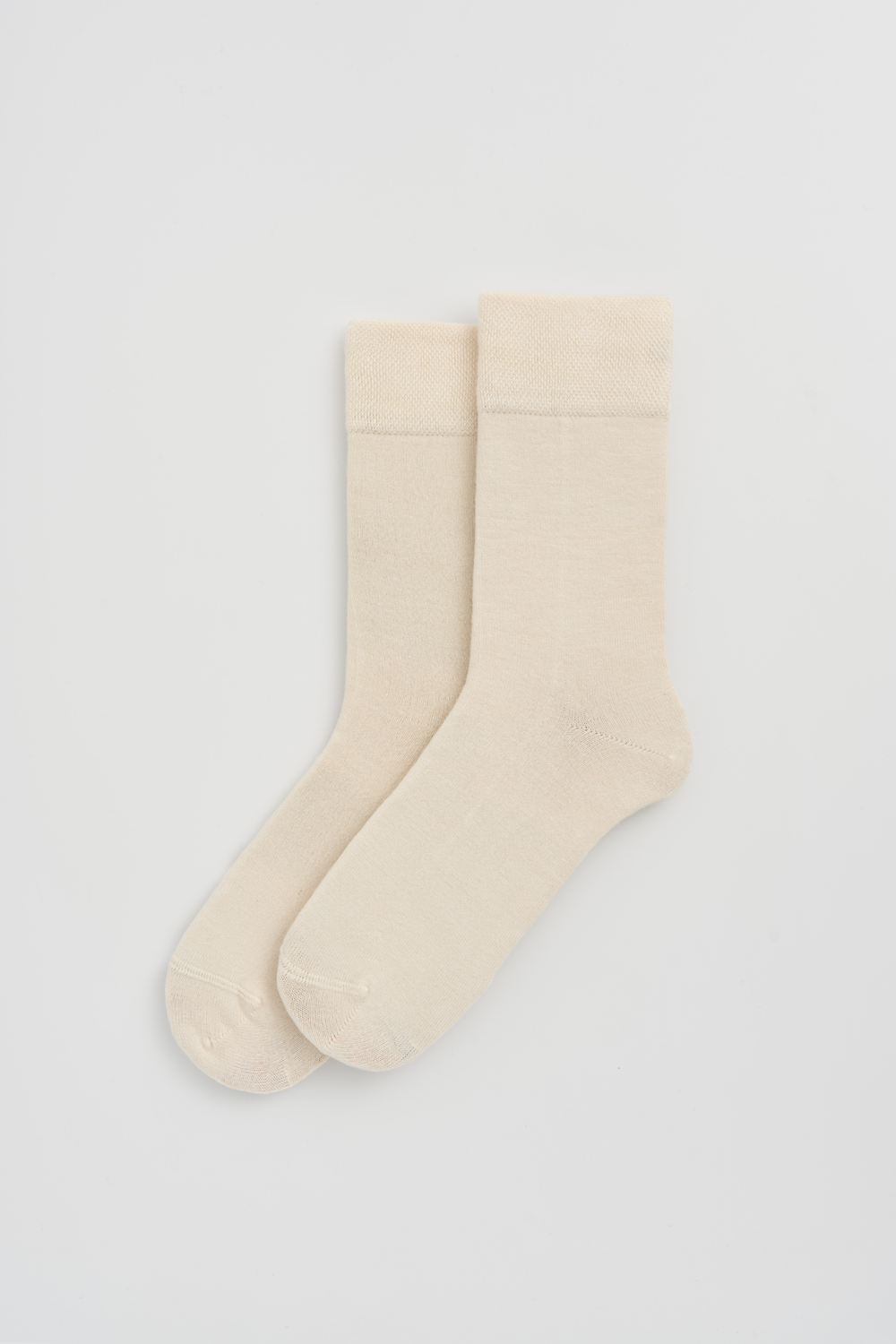 Pair of cream calf-length bamboo socks on a light grey background