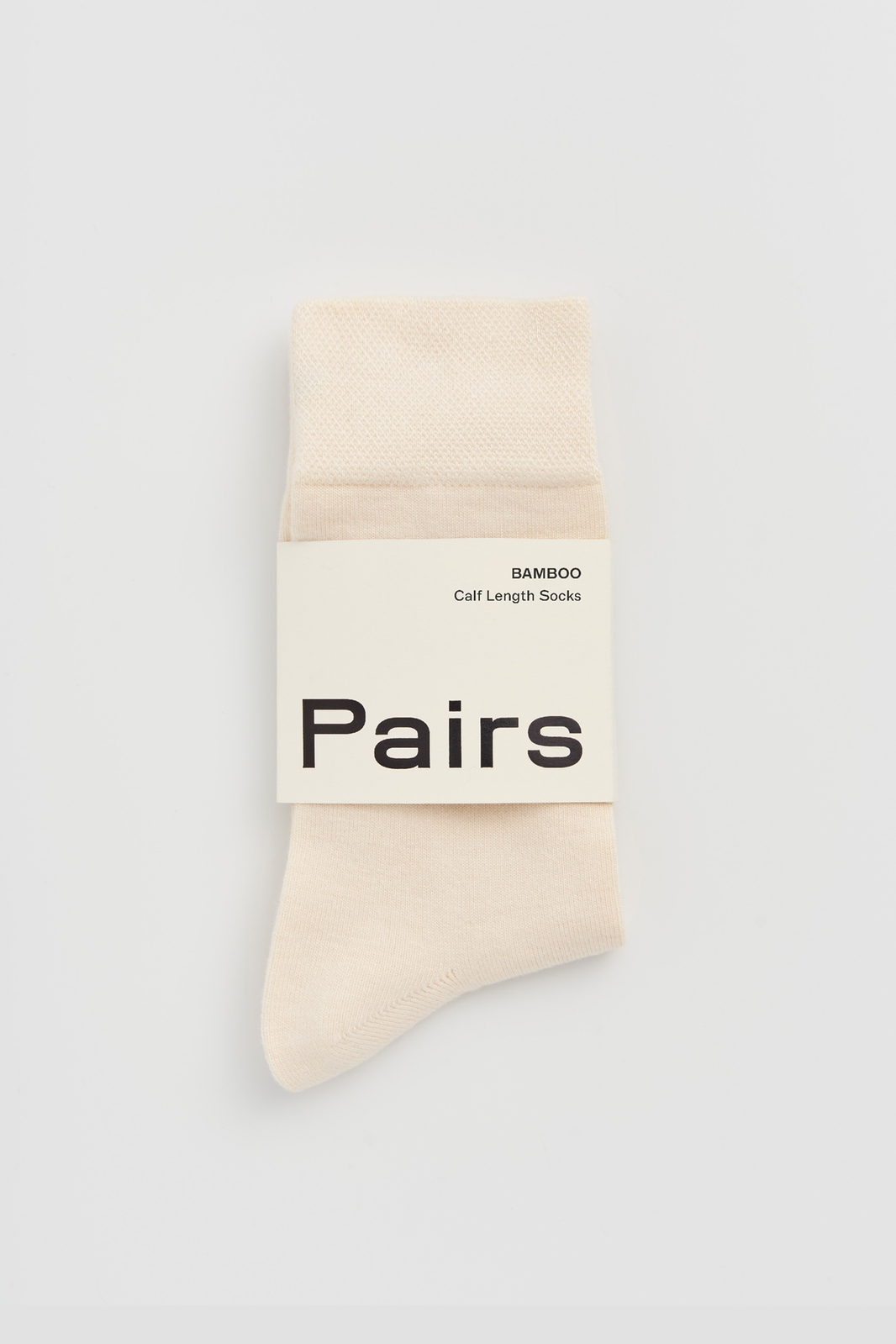 Cream calf-length bamboo sock with a 'Pairs' packaging band on a light grey background