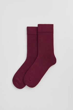 Pair of burgundy calf-length bamboo socks on a light grey background