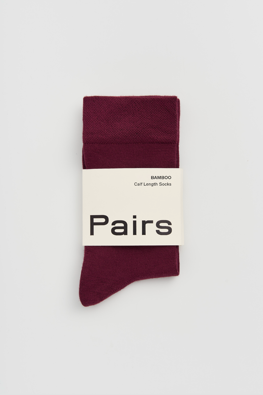 Burgundy calf-length bamboo sock with a 'Pairs' packaging band on a light grey background