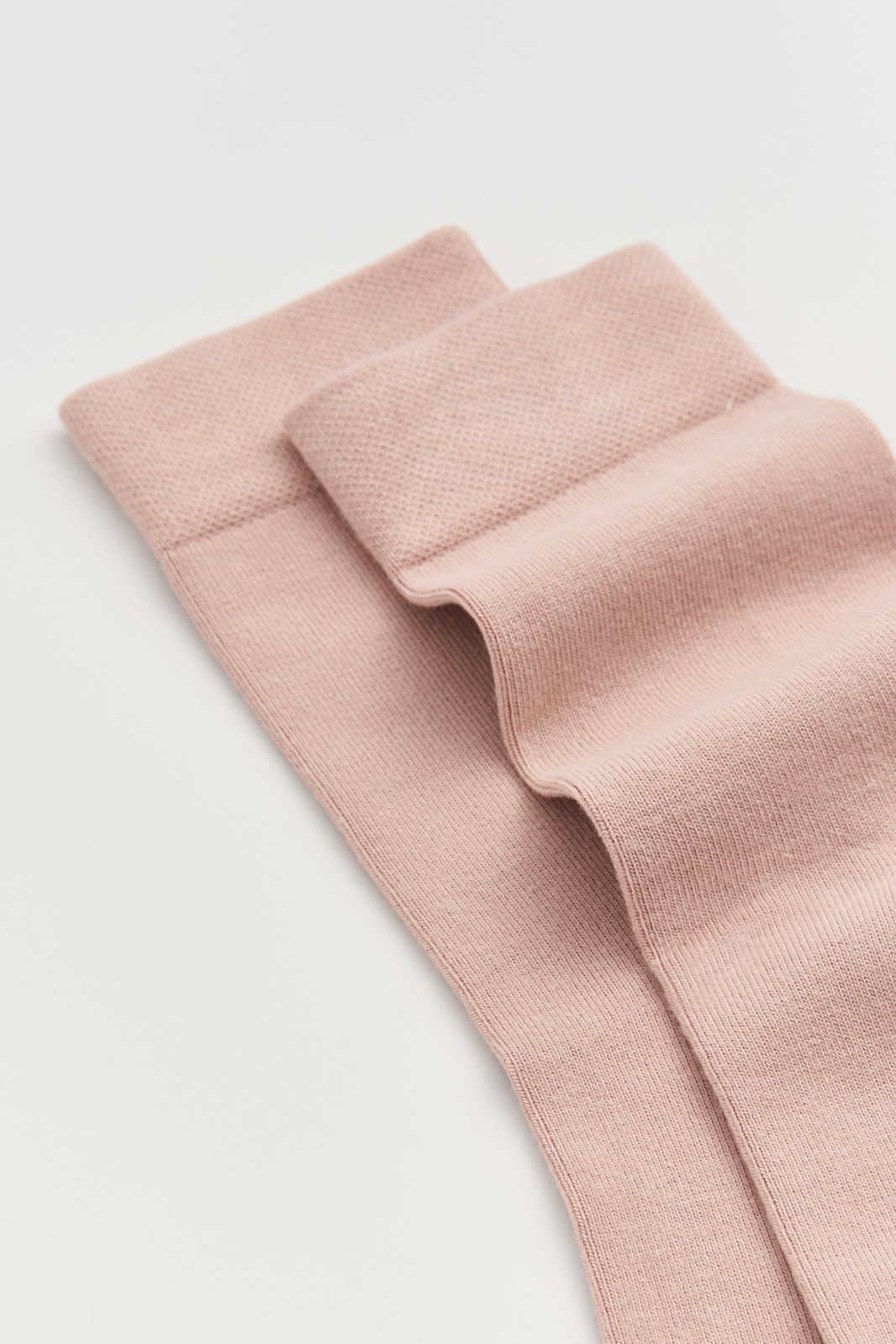 Close-up of a pair of pink calf-length bamboo socks on a light grey background