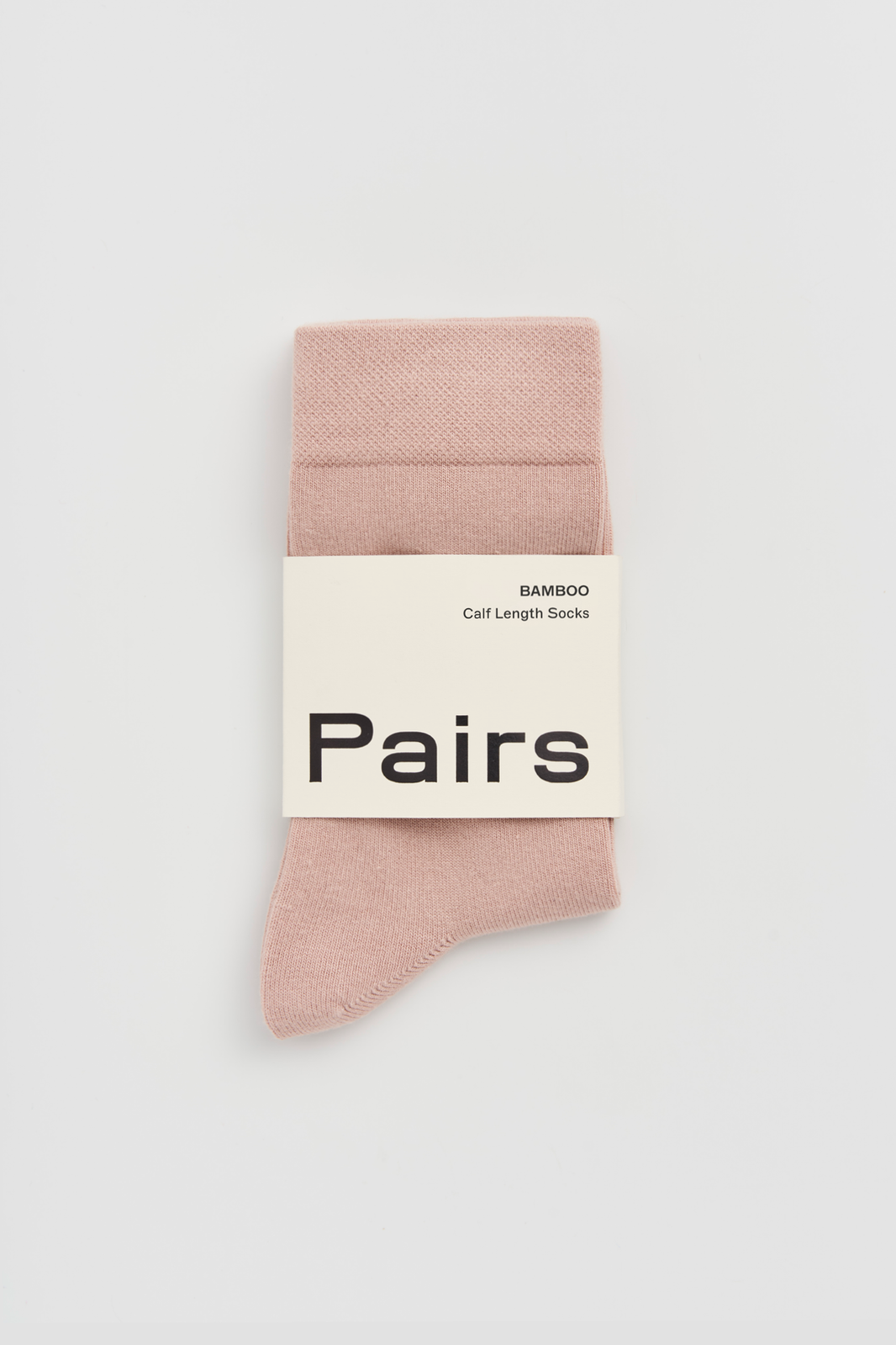 Pale pink calf-length bamboo sock with a 'Pairs' packaging band on a light grey background