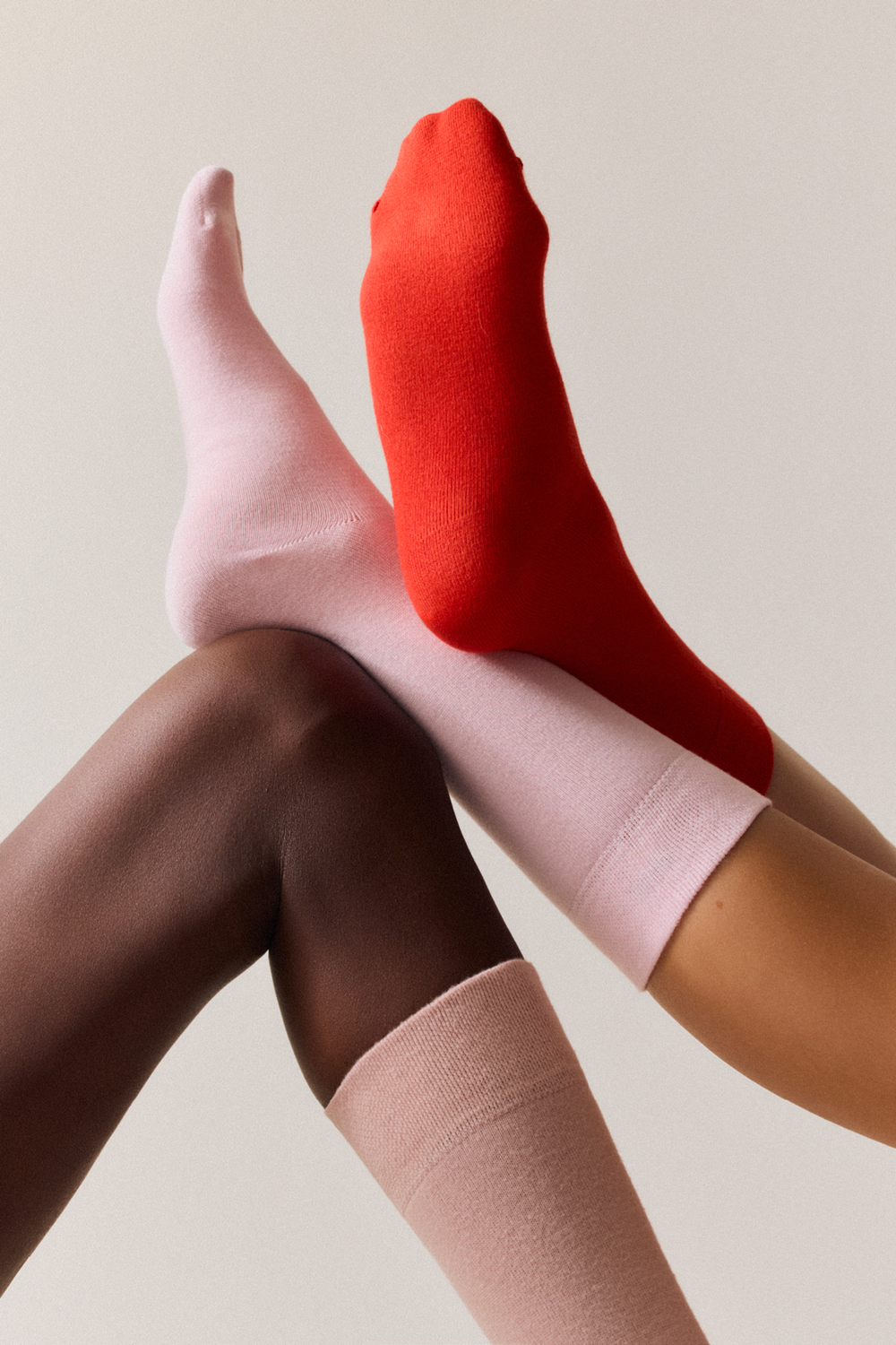 Three people wearing bamboo calf length socks, including light pink, on a neutral background.