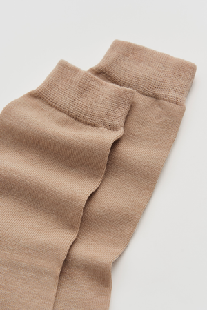 Pair of beige calf-length merino socks on a white background