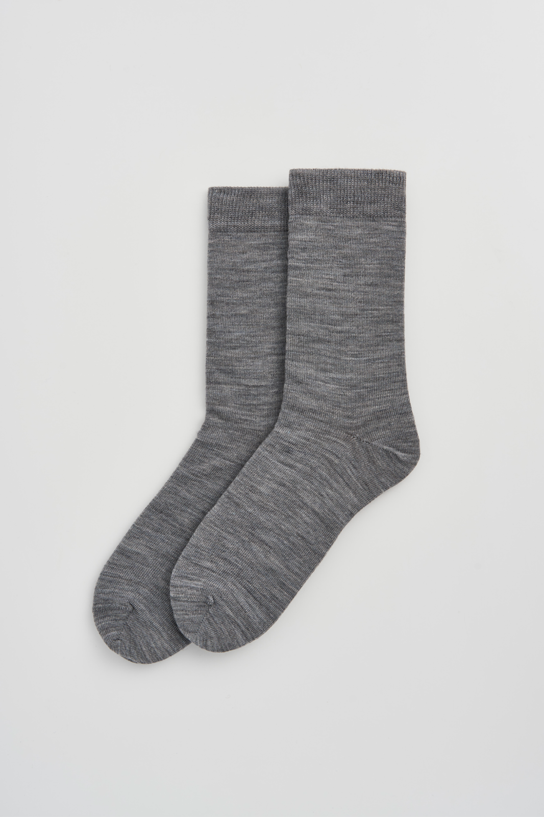 Pair of grey calf-length merino socks on a light grey background