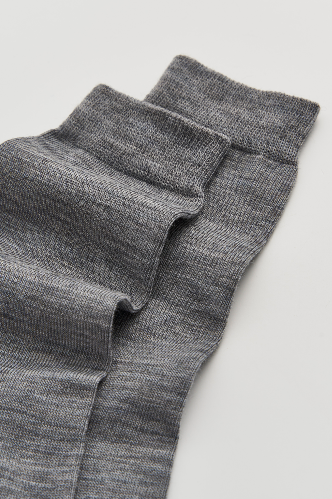 Close-up of the top of a pair of grey calf-length merino socks on a light grey background