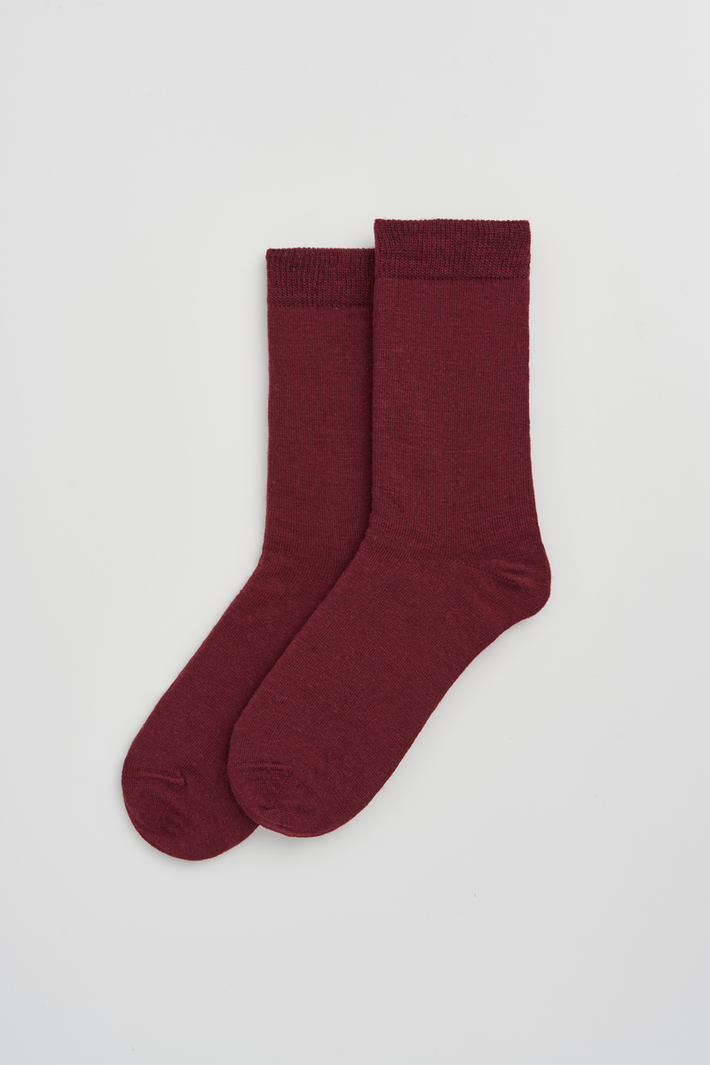 Pair of burgundy calf-length merino socks on a light grey background