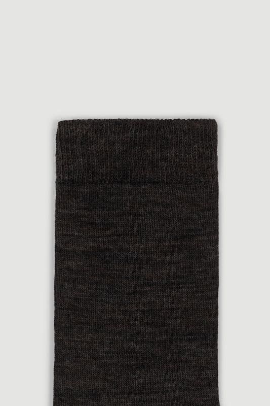 Close-up of the top of a dark brown calf length merino sock on a white background