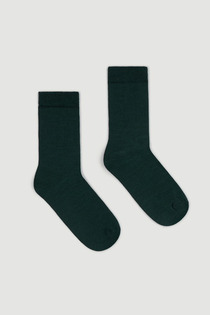 Pair of dark green calf length merino socks on a white background