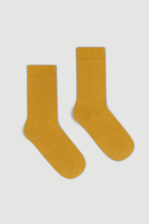 Pair of mustard yellow calf length merino socks on a white background