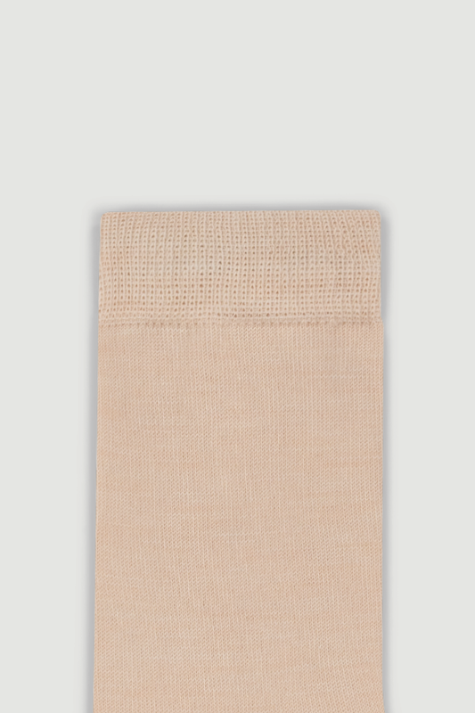Close-up of the top of a beige calf length merino sock on a white background