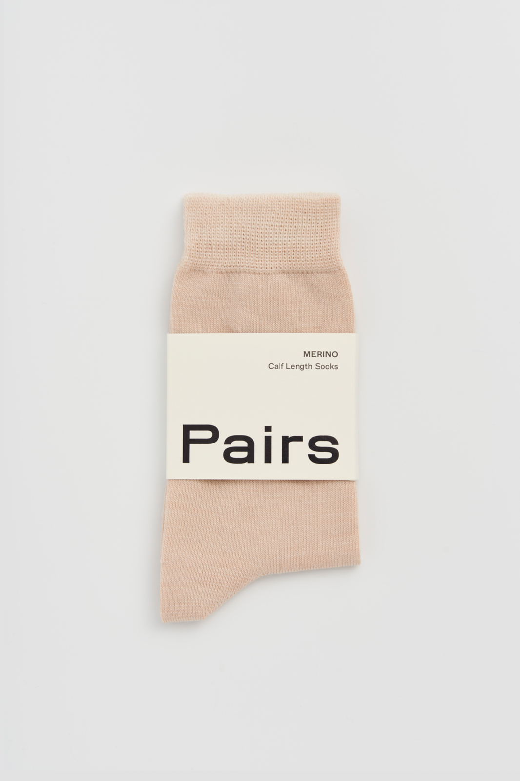 Light beige calf-length merino sock with a 'Pairs' packaging band on a light grey background