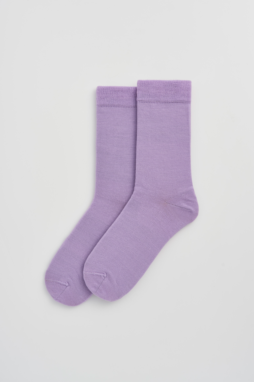 Pair of lilac calf-length merino socks on a light grey background