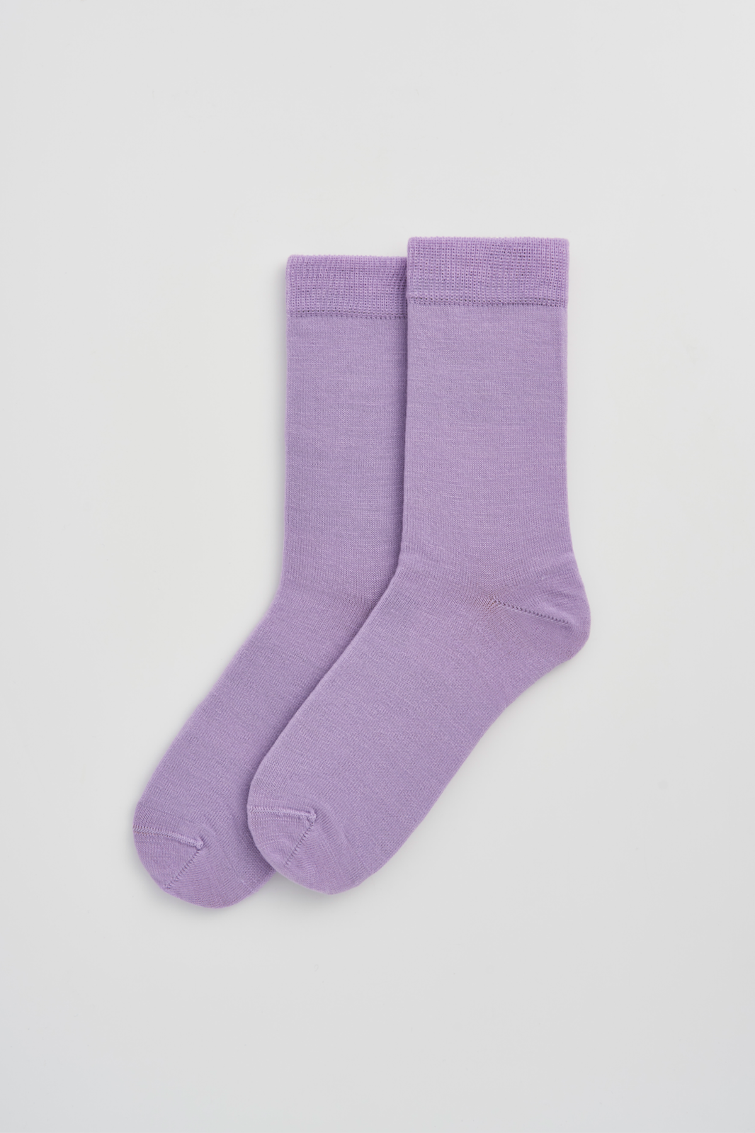 Pair of lilac calf-length merino socks on a light grey background