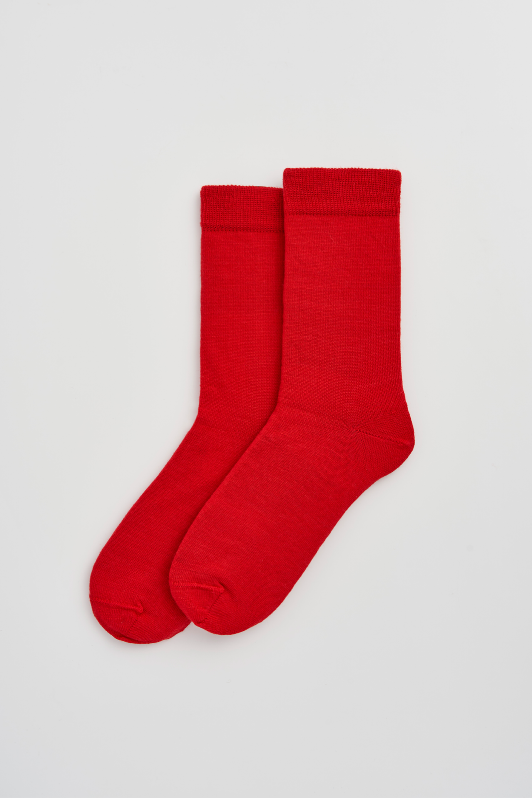 Red calf-length merino socks on a light grey background