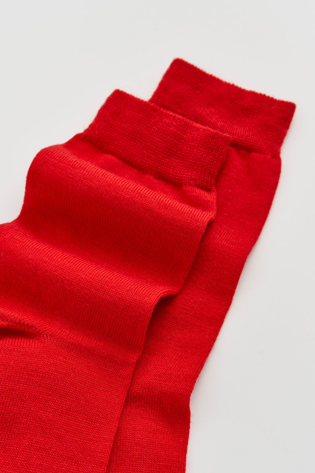 Red calf-length merino socks on a light grey background