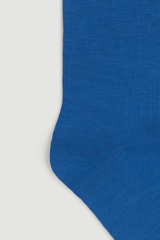 Close-up of the heel of a blue calf length merino sock on a white background