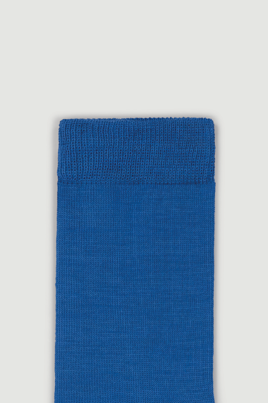 Close-up of the top of a blue calf length merino sock on a white background