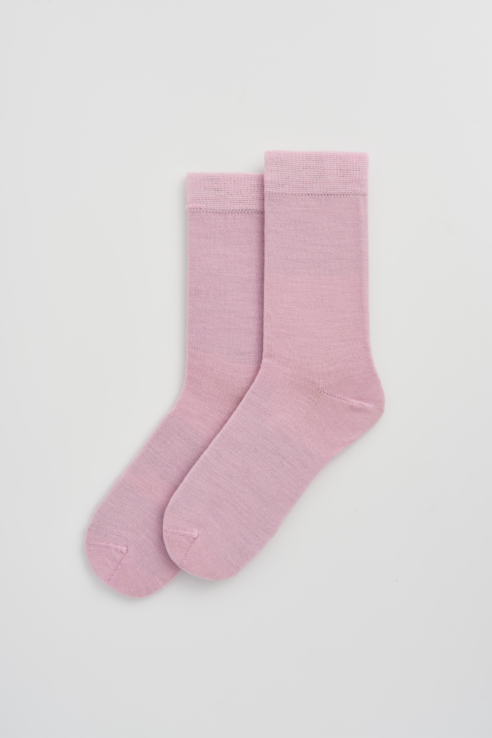 Pair of pink calf-length merino socks on a light grey background