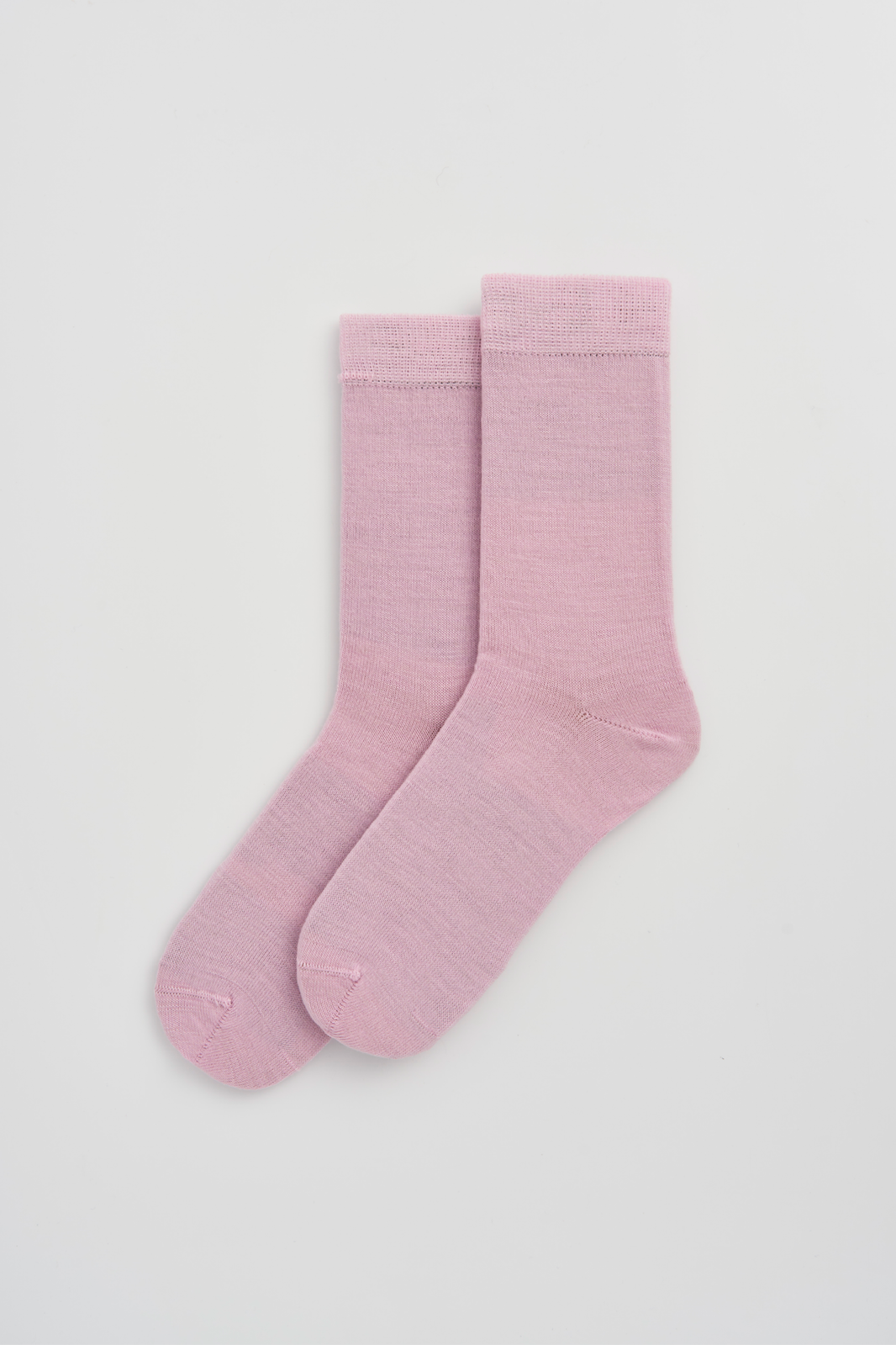Pair of pink calf-length merino socks on a light grey background