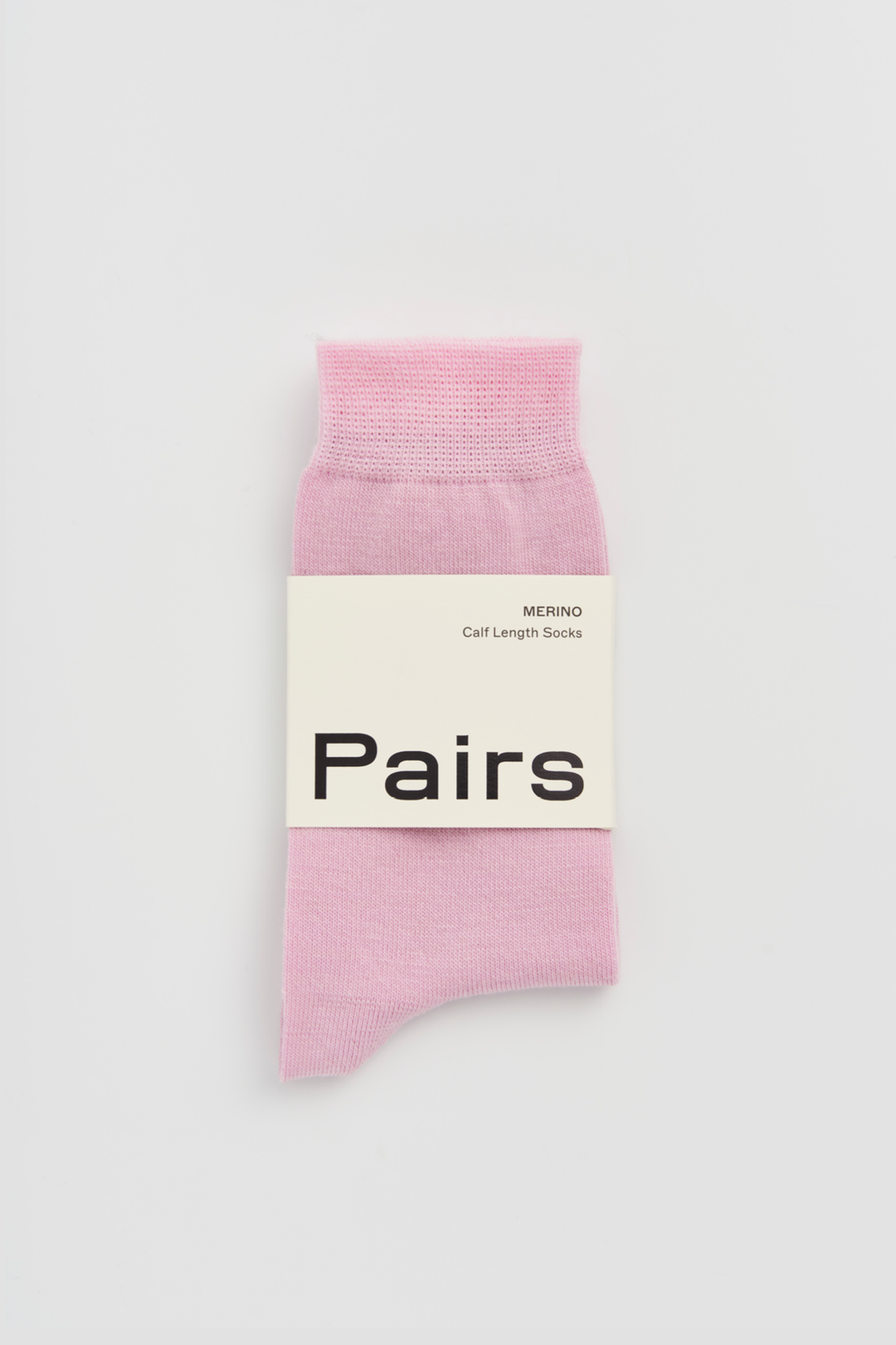 Pink calf-length merino sock with a 'Pairs' packaging band on a light grey background