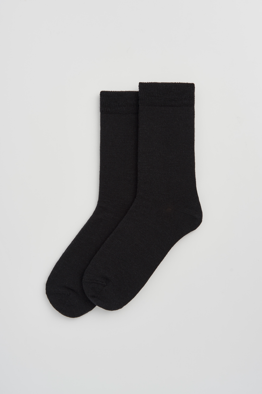 Pair of black calf-length merino socks on a light grey background