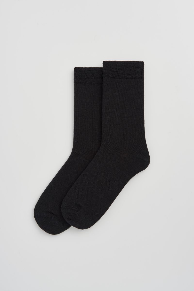 Pair of black calf-length merino socks on a light grey background