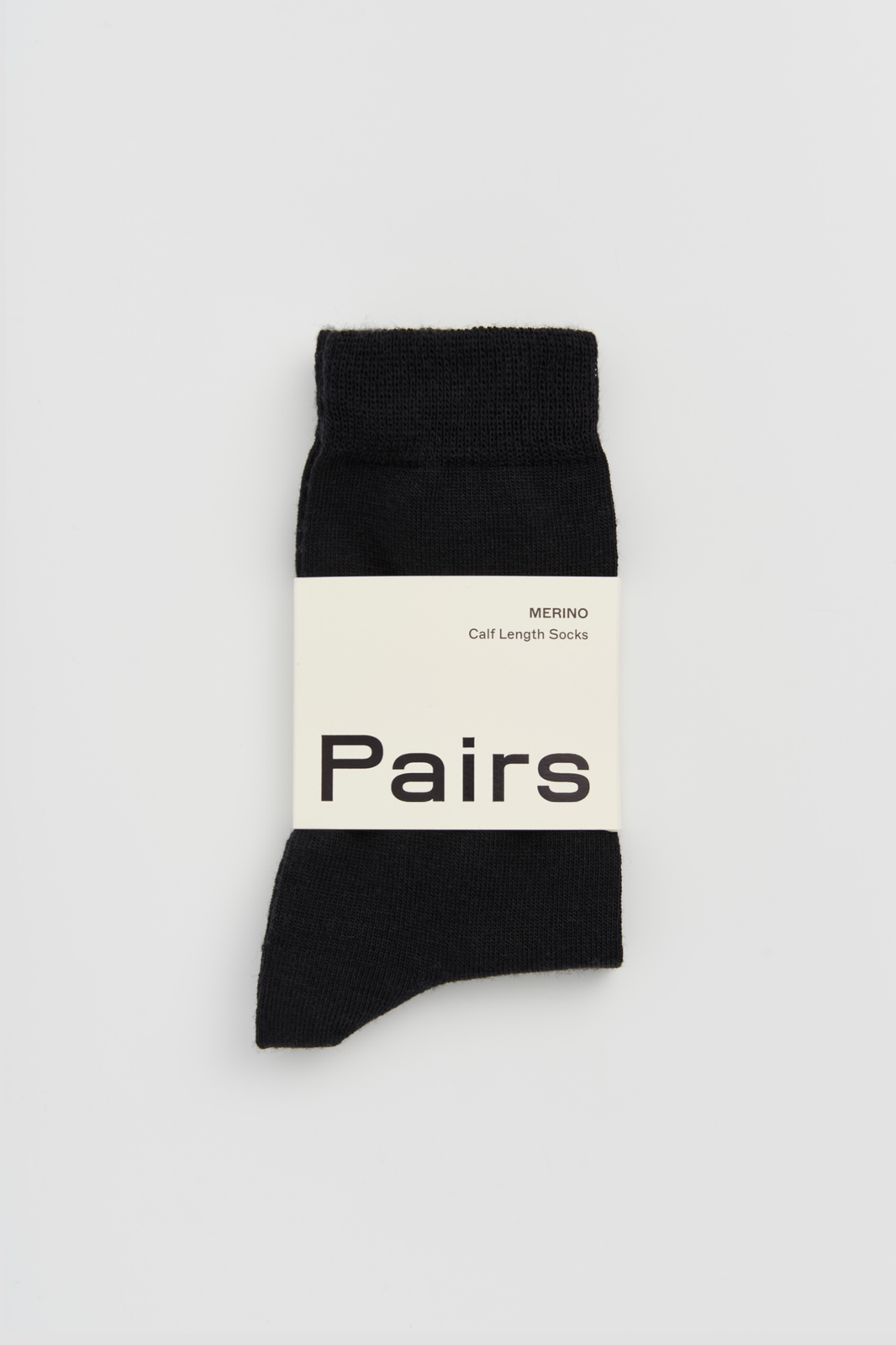 Black calf-length merino sock with a 'Pairs' packaging band on a light grey background