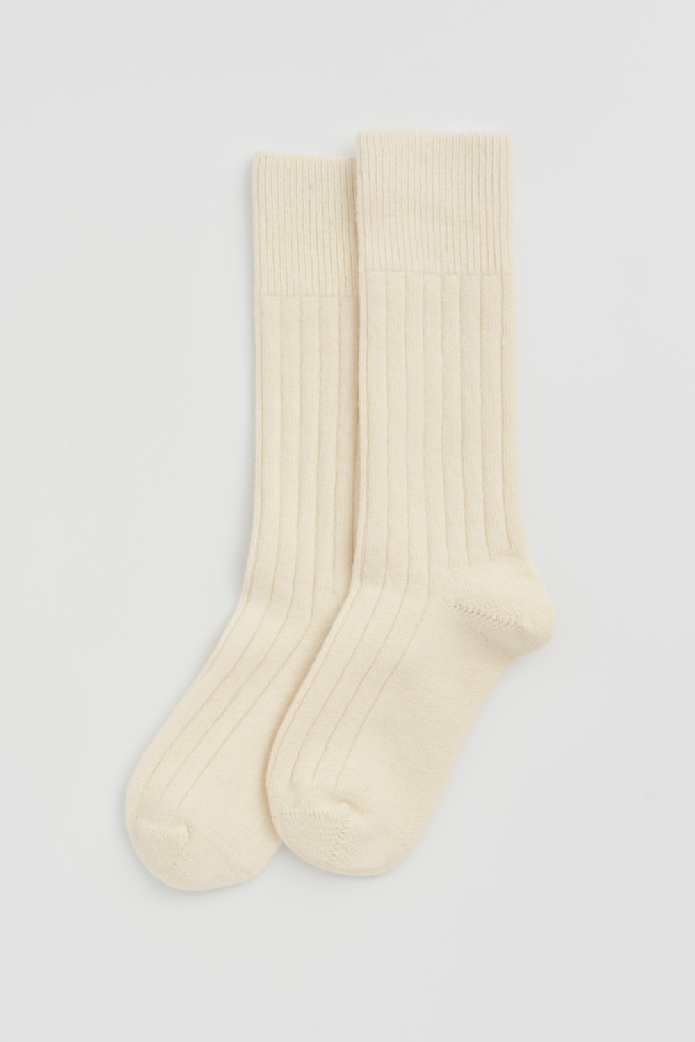 Pair of cream merino ribbed bed socks on a light grey background