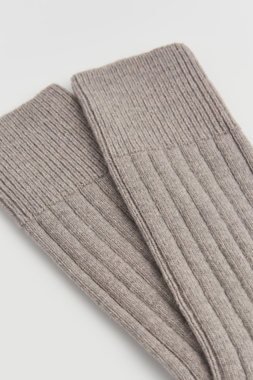 Close-up of the top of a pair of grey merino ribbed bed socks on a light grey background