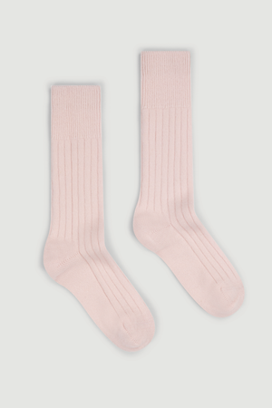 A pair of pale pink ribbed merino bed socks on a white background