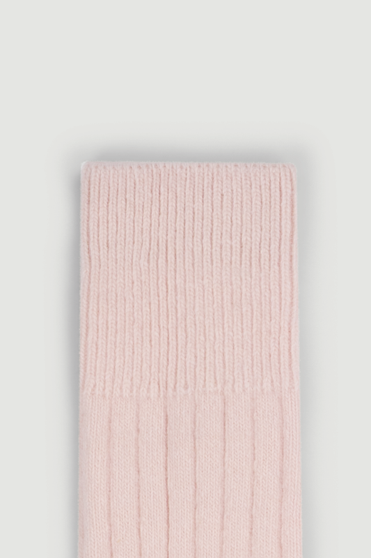 Close-up of the  top of a pale pink ribbed merino bed sock on a white background.