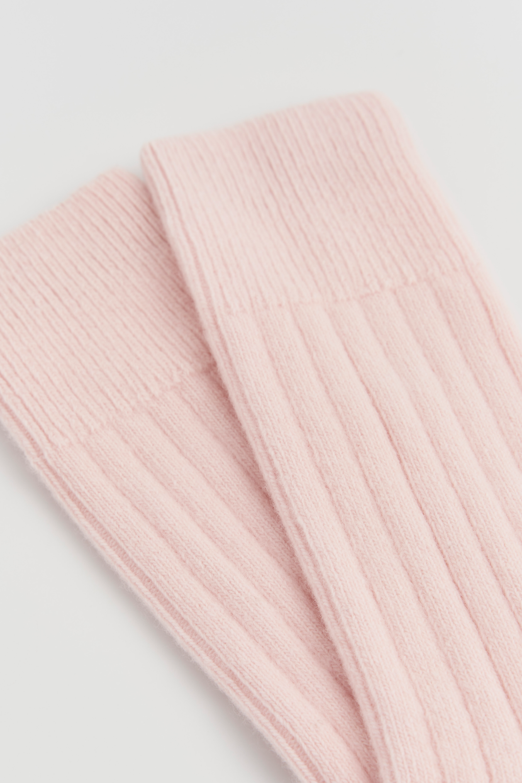 Close-up of pink ribbed merino bed socks on a light grey background