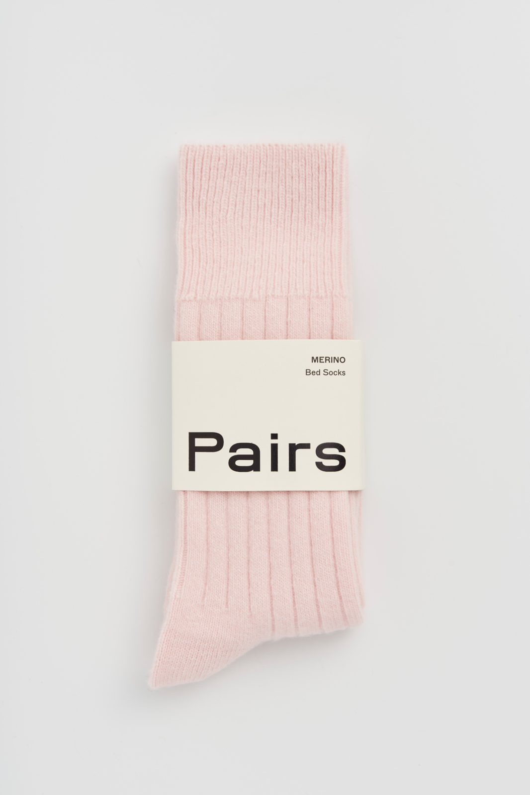 Pink ribbed merino bed sock with a 'Pairs' packaging band on a light grey background