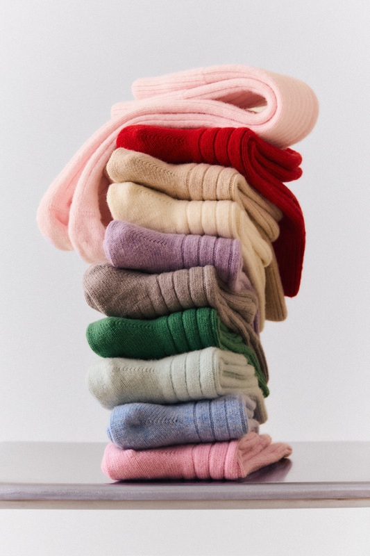 Stack of colorful folded merino ribbed bed socks on a white surface