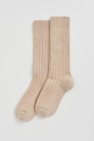 Pair of light beige merino ribbed bed socks on a light grey background