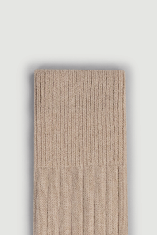 Close-up of the top of a beige merino ribbed bed sock on a white background