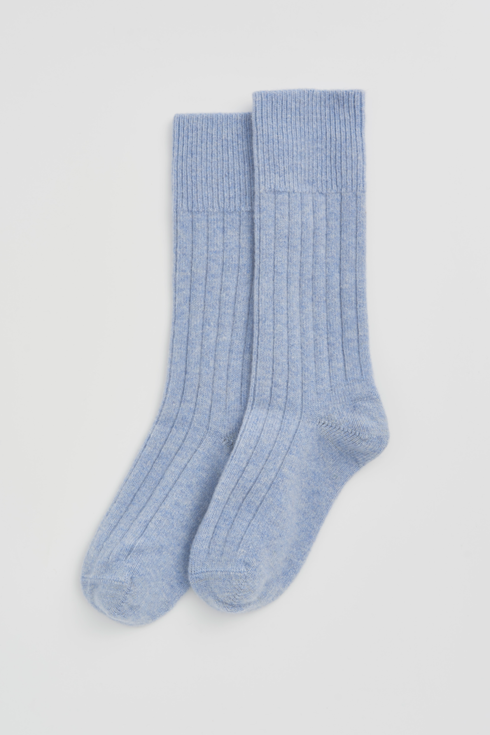 Pair of light blue merino ribbed bed socks on a white background