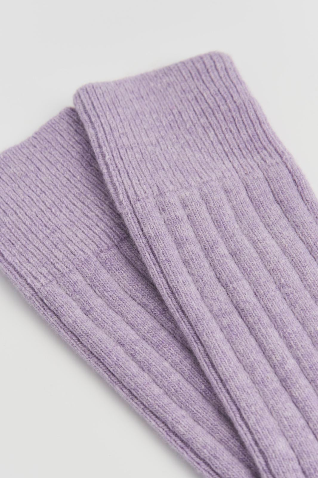 Close-up of the top of a pair of lilac merino ribbed bed socks on a light grey background