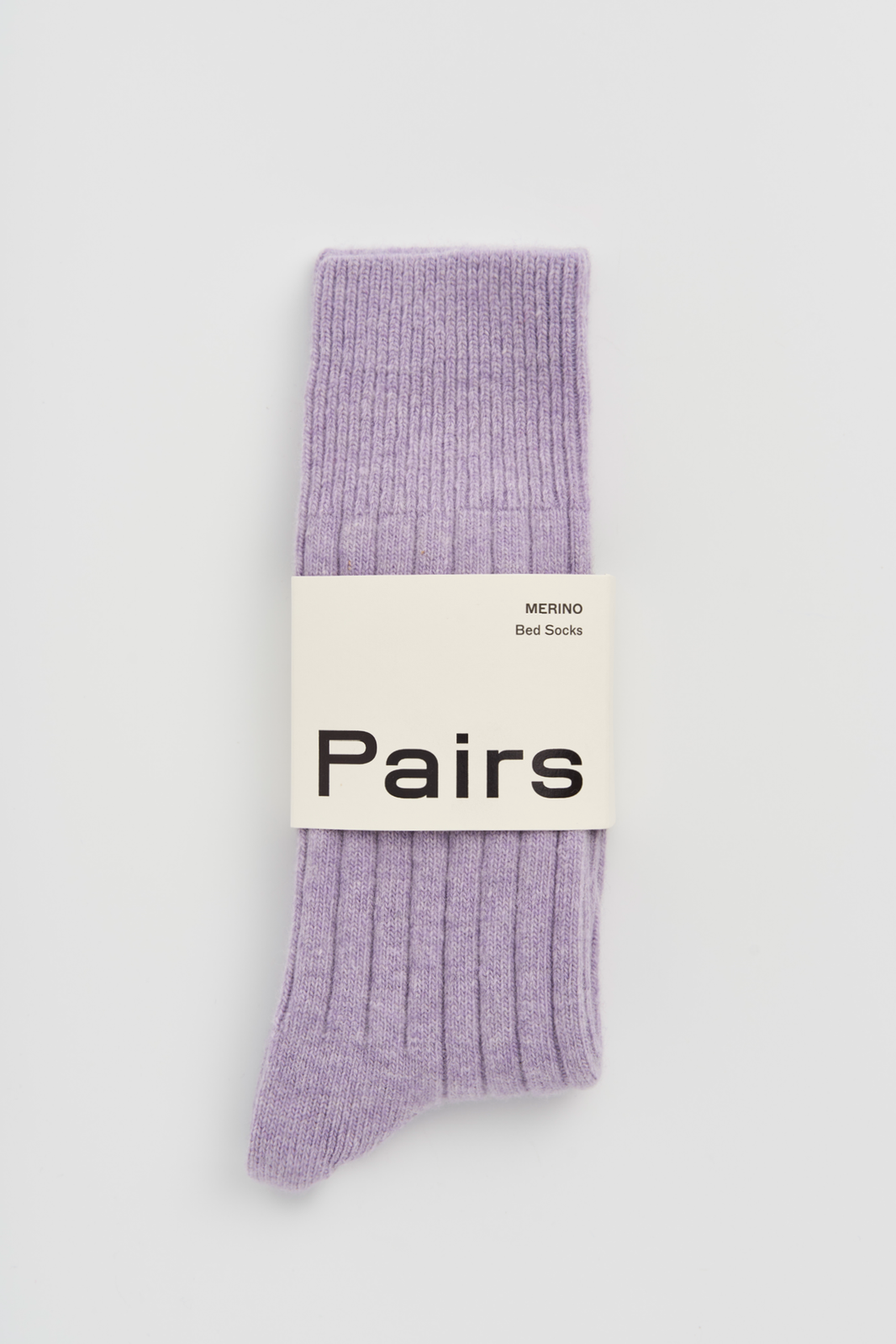 Lilac ribbed merino bed sock with a 'Pairs' packaging band on a light grey background