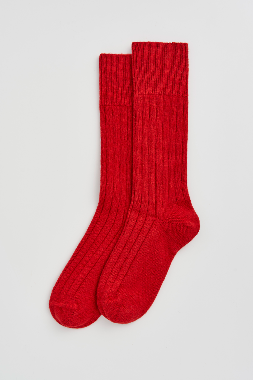 Pair of red merino ribbed bed socks on a light grey background