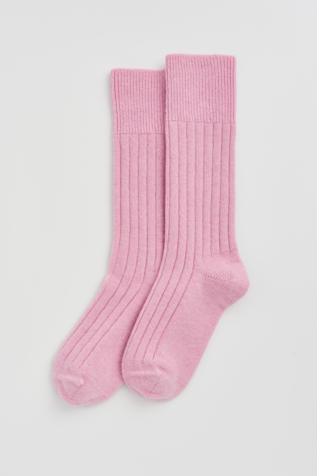 Pair of pink ribbed merino bed socks on a light grey background