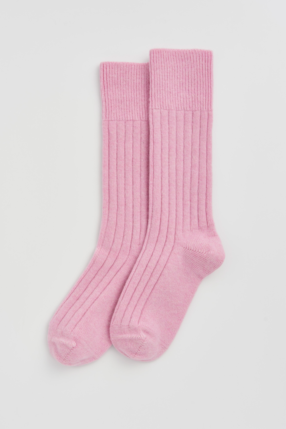 Pair of pink merino ribbed bed socks on a light grey background