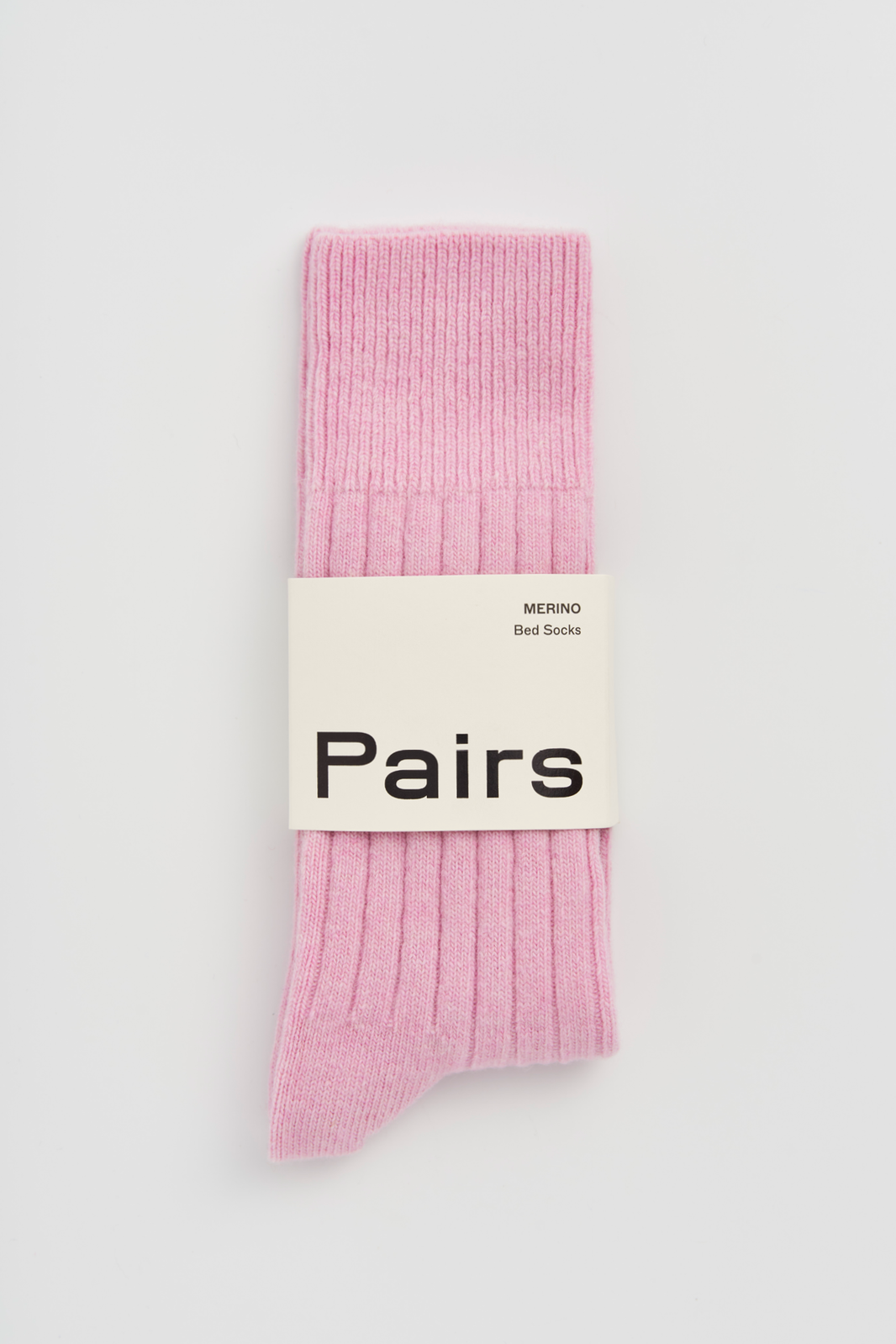 Pink ribbed merino bed sock with a 'Pairs' packaging band on a light grey background