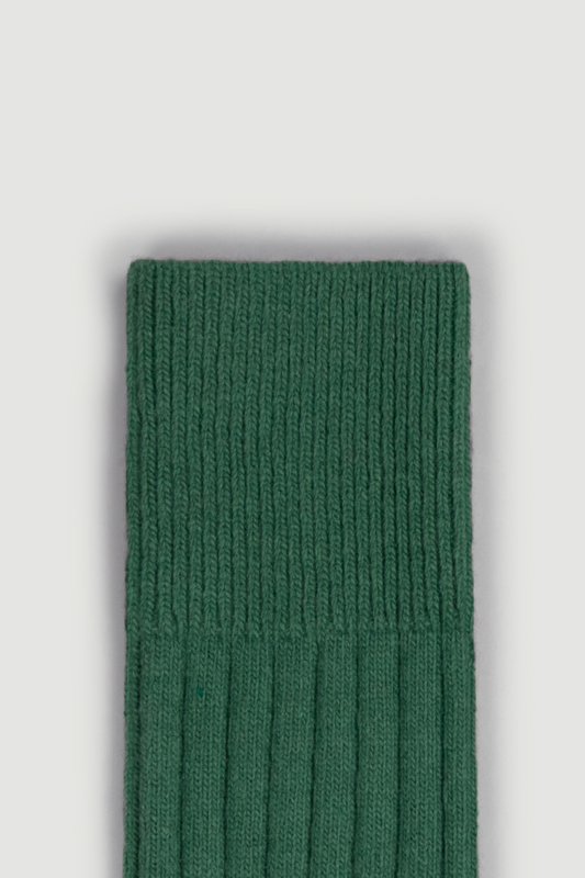 Close-up of the top of a green merino ribbed bed sock on a white background