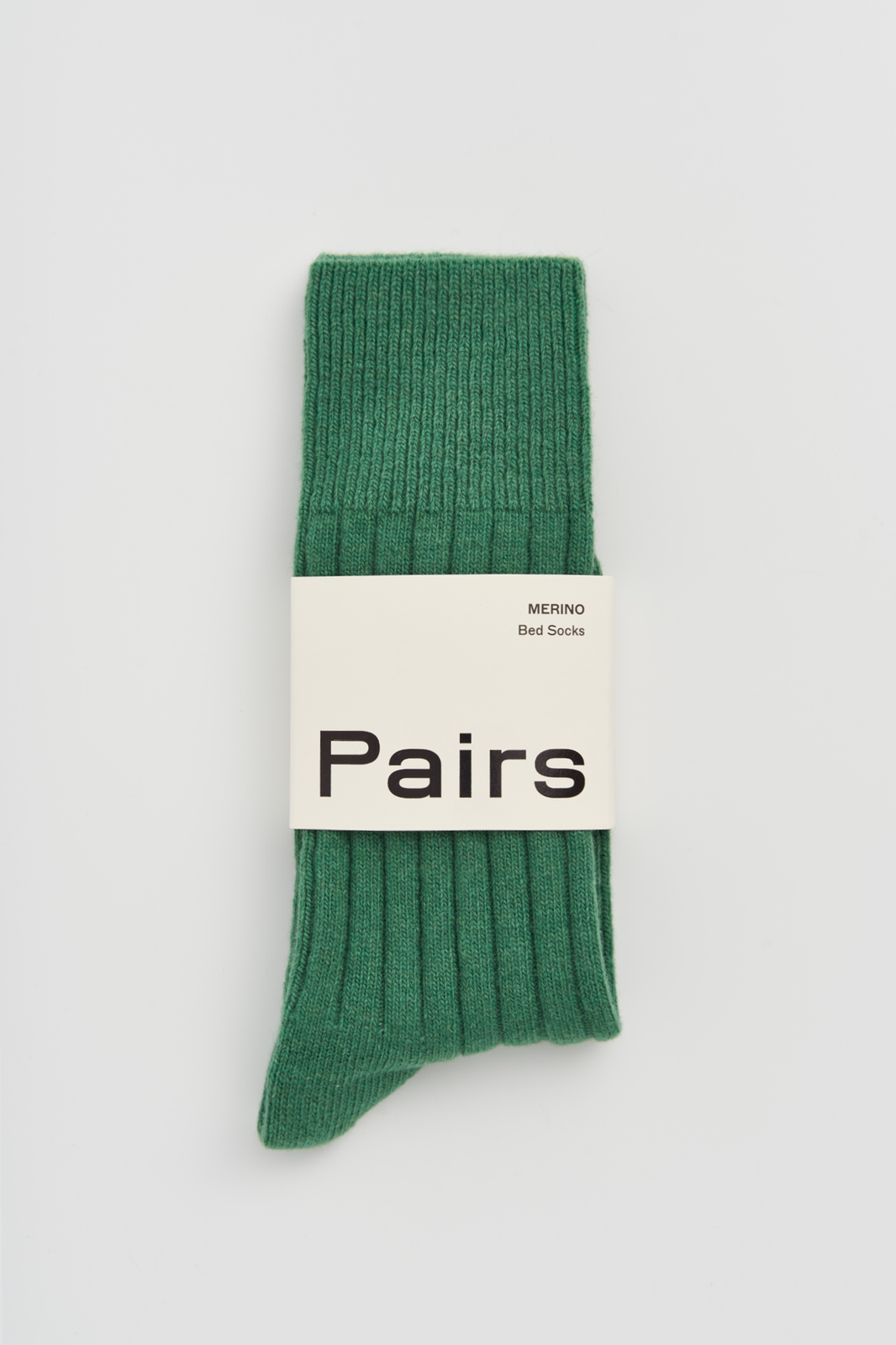 Green merino ribbed bed sock with a 'Pairs' packaging band on a light grey background