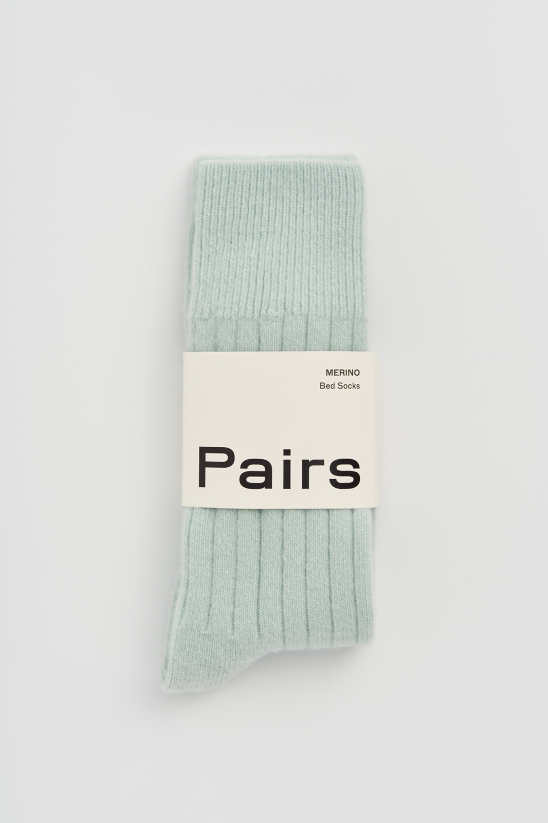 Minty green ribbed merino bed sock with a 'Pairs' packaging band on a light grey background