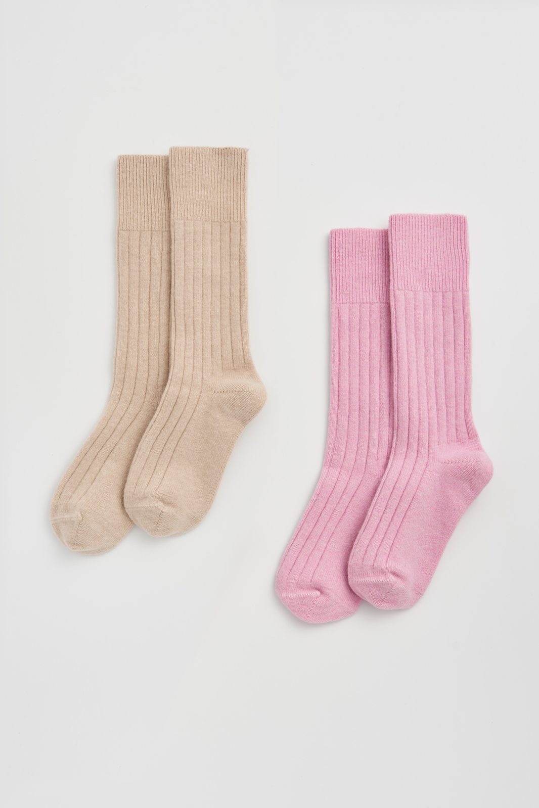 Two pairs of ribbed merino bed socks, one beige and one pink, on a light grey background.
