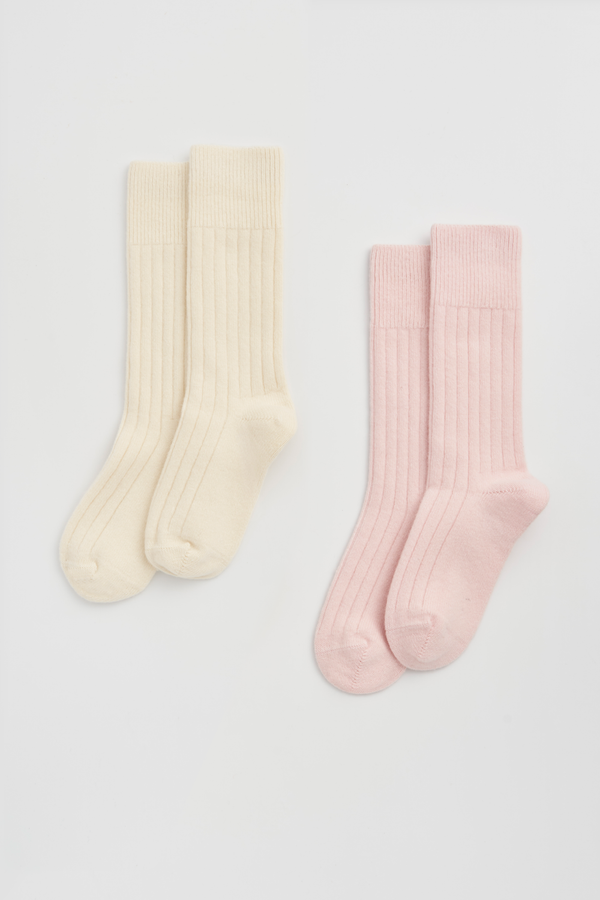 Two pairs of ribbed merino bed socks, one cream and one pink, on a light grey background.