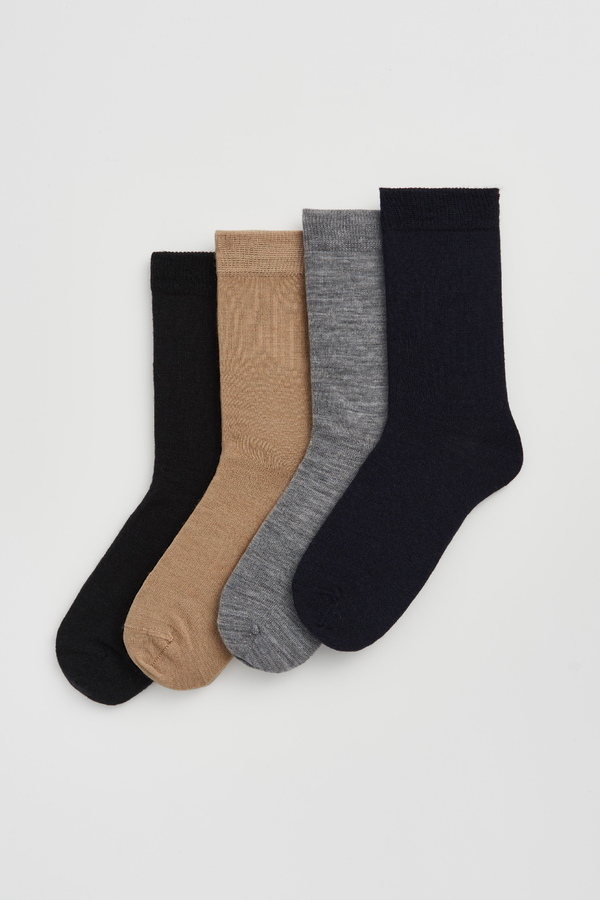 Four pairs of calf-length merino socks in black, beige, grey, and navy blue on a light grey background